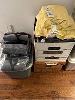 Boxes and bins containing folded women's sweaters in multiple colors including yellow and gray.