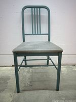 Front view of green painted metal chair with grey vinyl seat, showing the three vertical slats on the backrest.