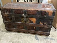 Front view of the antique wooden storage trunk showing metal latch and handle details.