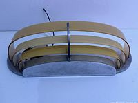 Front view showing chrome base and amber-beige curved glass panels in layered design mounted vertically with central chrome support.