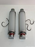 Top view showing two cylindrical chrome and glass wall sconces with wires and paint loss at both ends.