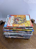 Stack of Nintendo Power magazines on wooden table, showing top issue featuring Mario & Sonic Music Games cover
