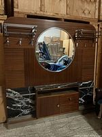 Full front view of hall mirror coat stand showing mahogany-veneered frame, round mirror, marble base panels, chrome hat shelf and hooks, lower cabinet.
