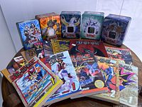 Photo showing a variety of Yu Gi Oh trading card game tins and manga volumes spread on a table.