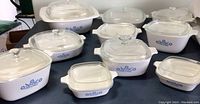 Full set of 10 Corningware Cornflower blue pattern baking dishes with lids on a table.