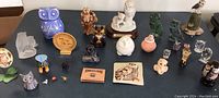 Overview of the collection showing a variety of owl figurines in different sizes and materials arranged on a table.