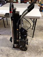 Upright view of entire log splitter showing handles, hydraulic beam, motor and wheels