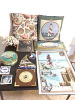 Overall view of the lot showing pillows, framed shell and painted art, weather gauge, coral piece, and nautical decor.