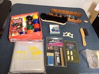 Complete set of pool table accessories on a table including Aramith pool balls, cue holders, chalk, brushes, and a sealed Imperial plastic cover.