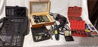 Full lot showing corded hammer drill, cordless drill, multiple drill bit sets, screwdriver bits, and wooden box with hole saws.
