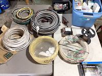 Overview of spools of wire, flexible conduit coil, fittings tray, blue bin, multimeter box