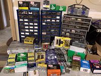 Overview of two blue and one gray multi-drawer cabinets with assorted boxes and tackle boxes in front