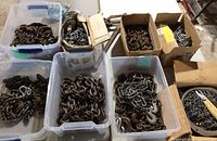 Multiple bins and boxes filled with various metal chains of differing sizes and link thicknesses.