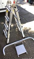 Overall view of folded Cosco aluminum ladder with curved stabilizer and platform accessories in front.