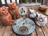 Photo of all six owl-themed outdoor decorations including two terra cotta candle holders, decorative owl plaque, two plastic owls, composite owl in holder, and round clock with thermometer