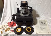 Craftsman router placed on black carrying case along with two router bits and manuals/manual booklets.