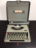 Photo showing the open vintage Tippa typewriter with detached red key in front.