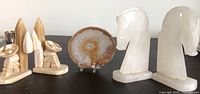 Carved onyx cactus and sleeping man figurine, white onyx chess knight bookends, and agate slice on display