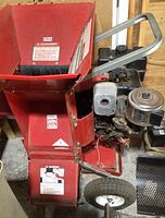 Front hopper, discharge chute, engine, and wheels of red Troy-Bilt wood chipper