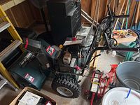 Overview side view of snow thrower showing entire machine and wheels in garage