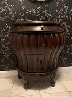 Front view of the demi lune cabinet showing curved ribbed panels, drawer and compartments with round knobs.