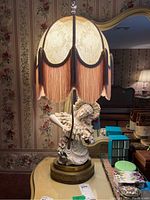 Front view of the figural Victorian style lamp showing the woman figurine and fabric fringe lampshade.