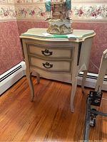 Pair of matching cream colored 2-drawer side tables with curved legs shown side by side.
