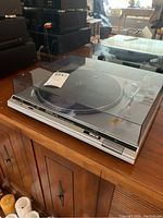 Full view of the Technics turntable with dust cover showing the overall unit on a wooden cabinet.