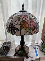 View of the full Tiffany style stained glass table lamp showing floral and butterfly motifs on the shade and ornate bronze base.