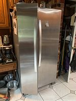 Full front and side view of Whirlpool stainless steel side-by-side refrigerator showing closed doors and vertical handles.