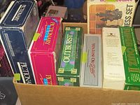 Top view of box showing multiple vintage board games including Pictionary, Outburst, Win, Lose or Draw, and Chess Set.