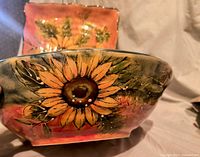 Close-up of bowl showing detailed sunflower painting with orange, green, and brown colors.