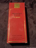 Front view of the red box packaging of Estée Lauder Modern Muse Le Rouge shimmer body lotion showing text and size.