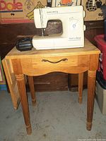 Euro-Pro 420 sewing machine sitting on wooden sewing table with drop-leaf sides extended, showing full setup.