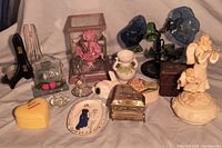 Photo showing the full assortment of vintage music boxes, jewelry boxes, and decorative knick knacks arranged on fabric surface.