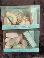 Two packs of new in box rainbow string lights, each pack containing 10 rainbow-shaped lights and a battery box.