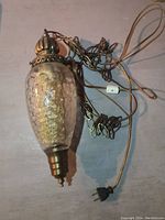 Full view of the vintage hanging lamp showing the glass body, brass metal fittings, and attached cord and chain for hanging.