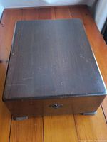 Top view of closed wooden rectangular box showing dark stain and surface scratches on lid.