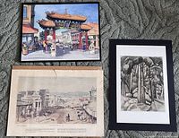 Three Victoria BC themed art prints together laid on carpet, showing a colorful Chinatown Gate print, a black-and-white Emily Carr print, and a sepia tone Yates Street print.