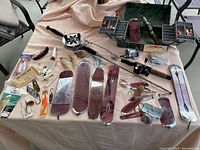 Full lot laid out on table showing old green Pete Henning Plano tackle box open with compartments filled with lures and fishing rod parts surrounding it.