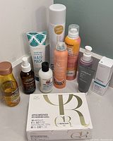 Photo showing all items in the lot arranged on a surface including hair masks, sprays, tonics, serums and boxed ampoules.