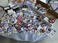 Photo showing wide spread of sports cards on a table including hockey, baseball, and football cards, some in boxes and some loose.