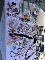 Overview of assorted crafting supplies spread on a surface including chains, beads, spools of wire, and packaged materials.