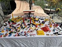 Wide view showing the entire lot of Playmobil toys including figures, animals, playground accessories, vehicles, and other accessories spread out on a white surface.