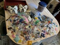 Overview of the lot spread out on a table showing many small bags of beads in multiple colors and two white butterfly-shaped items.