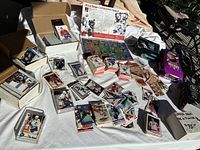 Wide view of large assortment of hockey cards and pin collection laid out on a table with boxes and loose cards scattered.