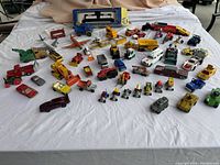 Full assortment of die-cast vehicles spread on white cloth