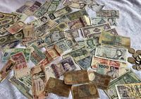 Spread of numerous paper banknotes and a small stack of coins on fabric background