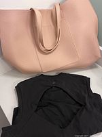 Photo shows light pink large tote bag with two long handles, textured material, and a front pocket. Bag appears clean and in like-new condition.