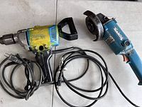 Makita drill and grinder set laid out showing cables and handles